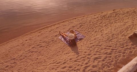 Woman and Dog Relaxing on Tranquil Beach at Sunset