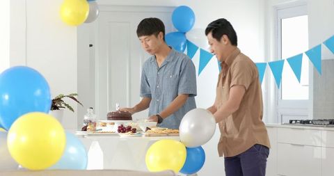Friends setting up birthday party with cake and snacks