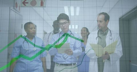 Medical team discussing data with digital devices in hospital corridor