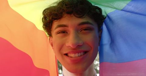 Smiling young man celebrating diversity with rainbow flag
