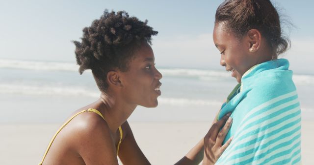 Mother wrapping daughter in towel at beach on sunny day - Download Free Stock Images Pikwizard.com