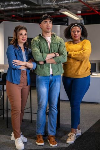 Diverse team standing confidently with arms crossed in modern open plan office workspace
