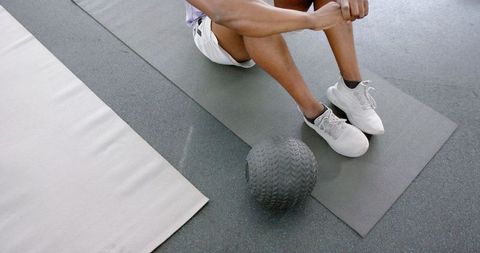 Athlete takes rest on gym floor with medicine ball for post-workout recovery