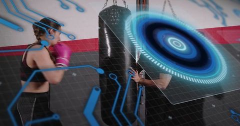 Female boxer training with coach at heavy bag with futuristic digital hud overlay