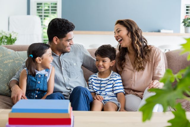 Family enjoying quality time together on a sofa in a cozy living room. Perfect for use in advertisements, family-oriented content, parenting blogs, and lifestyle articles. Highlights themes of happiness, togetherness, and home life.