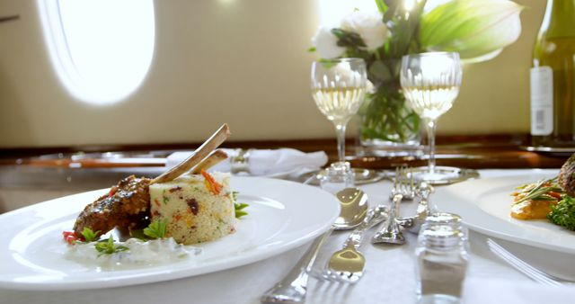 This image depicts a high-end dining experience aboard an airplane, with a lavish gourmet meal and glasses of white wine elegantly arranged on a table. This can be used in travel promotions, airline advertisements, luxury lifestyle blogs, and culinary magazines to highlight exquisite in-flight services and premium experience.