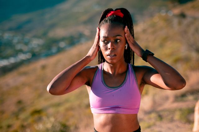 Fit african american woman exercising in countryside at sunset, wearing wireless earphones. healthy active lifestyle and outdoor fitness.