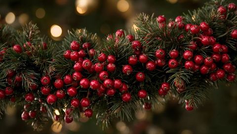 Evergreen Garland Featuring Glossy Red Berries and Warm Bokeh Lights for Holiday Decor