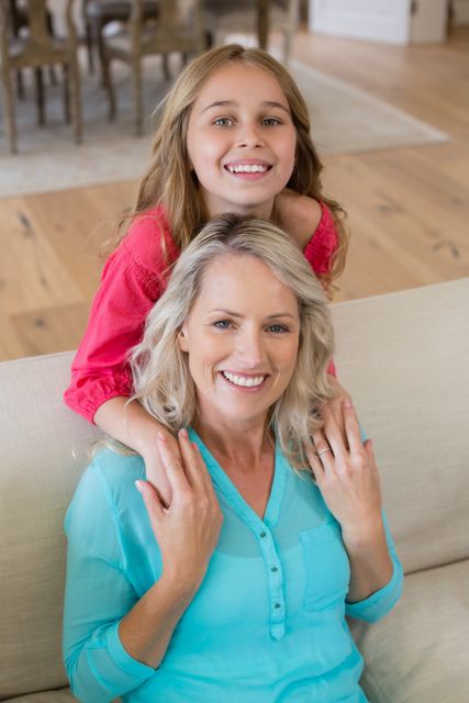 Portrait of mother and daughter smiling in living room at home
