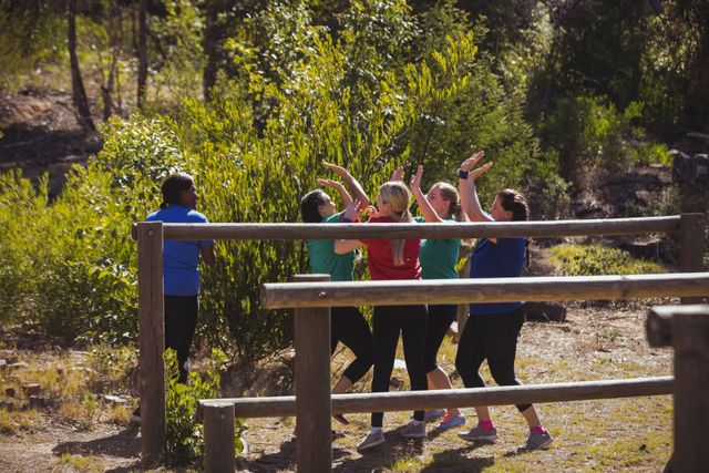 Group of fit women giving high five to each other in an outdoor boot camp on a sunny day. Ideal for promoting fitness programs, team-building activities, outdoor adventures, and healthy lifestyle campaigns.