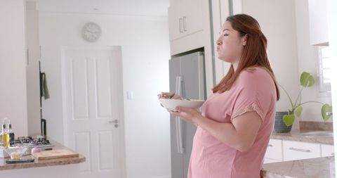Plus Size Woman Enjoying Fresh Salad in Modern Kitchen
