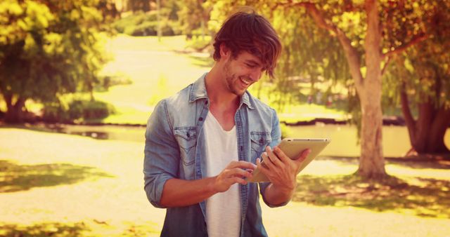 Smiling Man Using Tablet Outdoors in Sunny Park - Download Free Stock Images Pikwizard.com