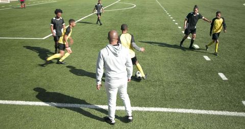 Coach Leading Soccer Team in Dynamic Practice Drills on Field