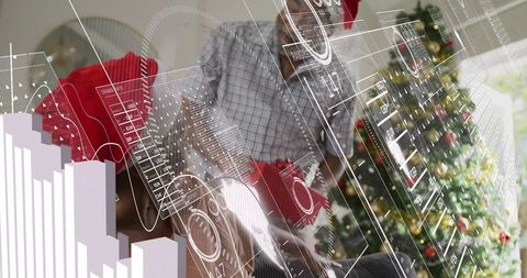 Senior couple wearing santa hats using tablet with digital data overlays near christmas tree