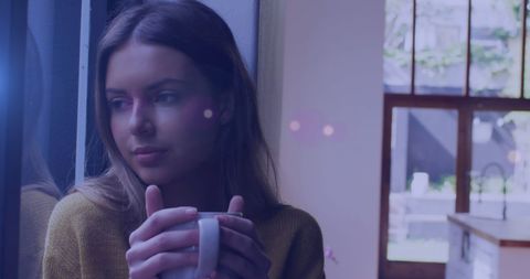 Woman Relaxing While Drinking Coffee by Window at Home