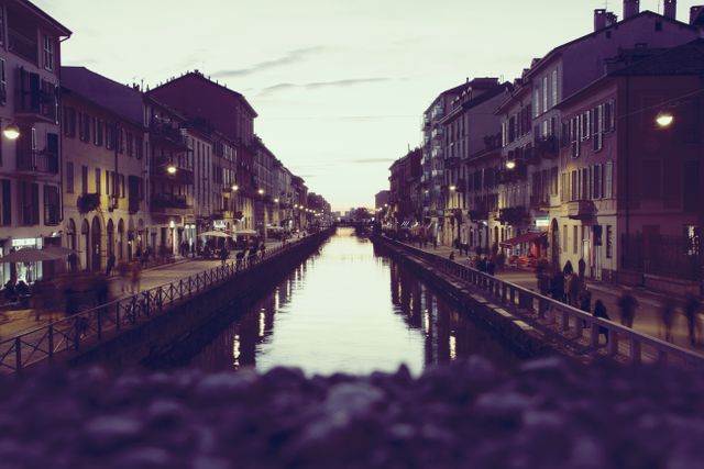 Twilight view showing historic waterfront district with old buildings lining a peaceful canal. Street lights and reflections in the water create a stunning ambiance. Ideal for showcasing cityscapes, travel destinations, and architectural designs.