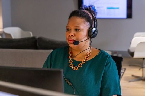 African american customer support agent wearing headset working at open-plan office desk