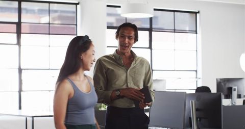 Happy colleagues discussing work in open office setting