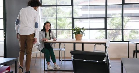 Modern office colleague interaction near window