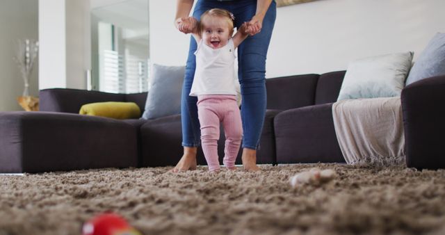 Young mother assisting baby girl with first steps at home - Download Free Stock Images Pikwizard.com