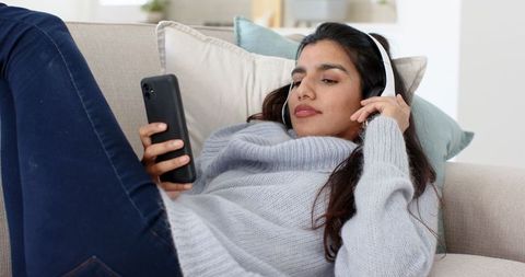 Casual Comfort at Home: Woman Relaxing with Headphones and Smartphone