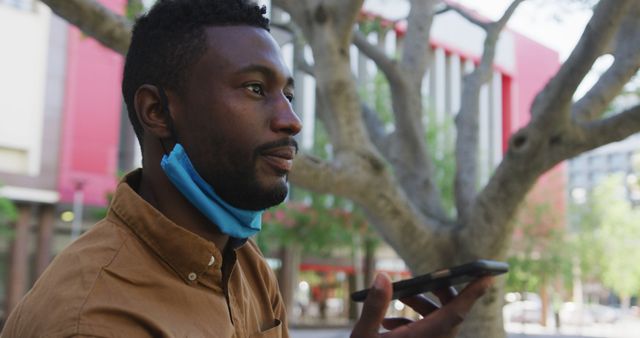 Man in Brown Shirt Using Smartphone Voice Command Under Tree - Download Free Stock Images Pikwizard.com