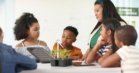 African american teacher guiding diverse students exploring renewable energy projects