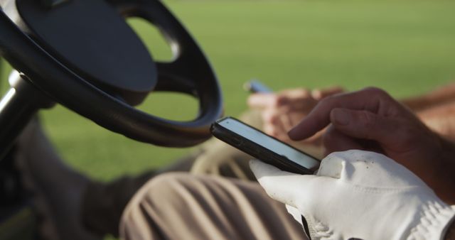 Caucasian male golf player sitting in golf cart and using smartphone. Golf, sport, technology and active lifestyle.