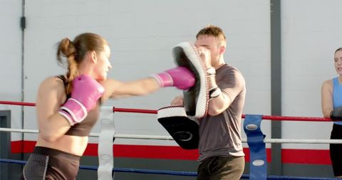 Female Boxer Delivering Powerful Straight Punch During Sparring with Coach in Ring