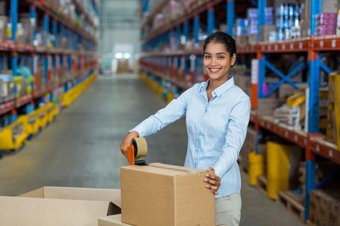 Hispanic woman efficiently packing boxes in warehouse environment