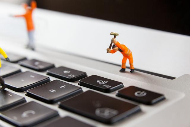 Ideal for illustrating concepts of technology maintenance, teamwork, and problem solving, this image features tiny worker figures performing repair tasks on a laptop keyboard. Useful for tech blogs, office presentations, and creative advertising campaigns.