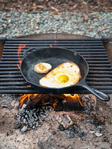 Egg in a Basket Cooking in Outdoors Cast Iron Skillet Over Fire