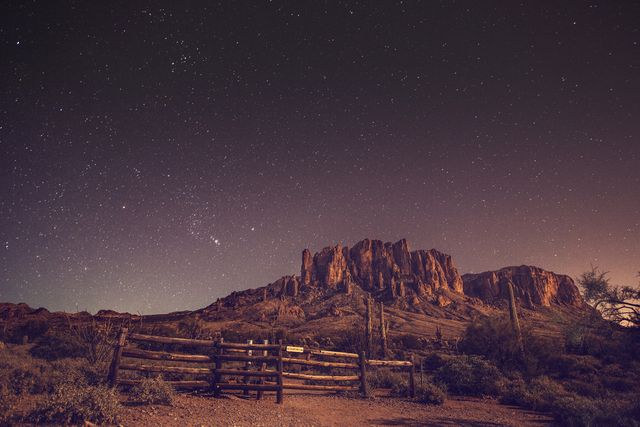 Stunning nighttime mountain range scene under starry sky, highlighting desert landscape beauty. Ideal for use in nature or travel websites, blogs about night photography, astronomy-related content, and posters aimed at promoting outdoor adventures and exploration.