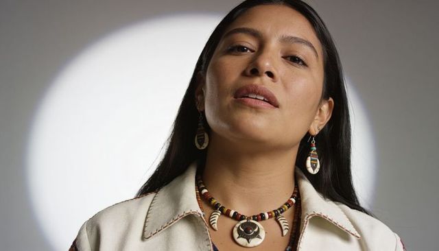 Confident woman wearing handcrafted bead necklace and shell pendant in spotlight portrait