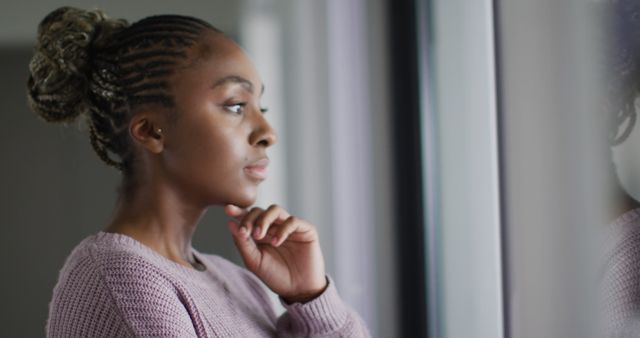 Thoughtful african american woman looking outside window. Lifestyle, relaxing and spending free time at home.