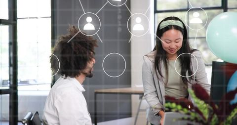 Office team collaborating over laptop behind glass partition with network overlay in modern workspac