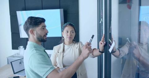 Colleagues Brainstorming Ideas on Glass Board in Modern Office