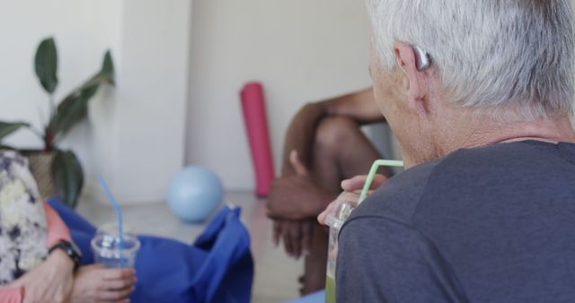 Senior individuals sitting together, drinking smoothies and engaging in a friendly conversation. Ideal for health and wellness themes, promoting social interaction among elderly, or showcasing a relaxed and healthy lifestyle in a senior community.