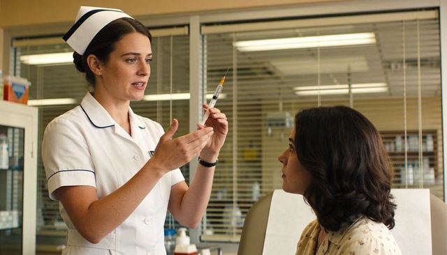 Nurse preparing injection while explaining procedure to patient in clinic