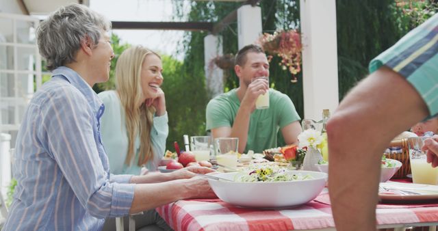 Happy caucasian family sitting at table in garden, eating dinner. Lifestyle, domestic life, family, and togetherness.