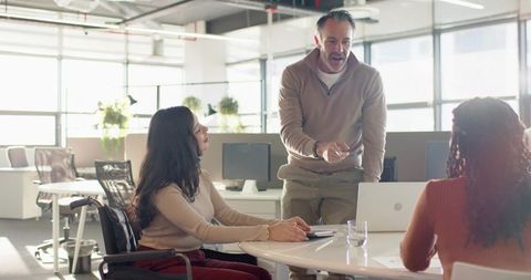 Leading diverse team during inclusive collaboration at open-plan office round table