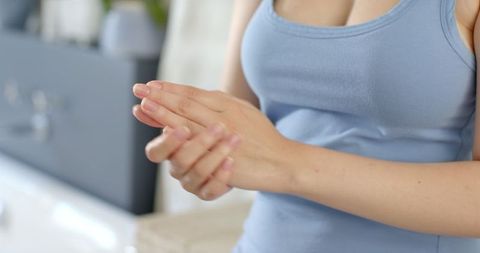 Woman in Bathroom Applying Lotion on Hands for Skincare Routine
