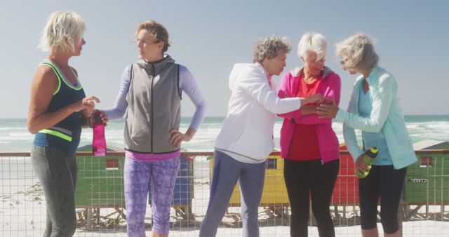 Diverse group of women wearing sports clothes talking at beach. Sport, active and healthy lifestyle.