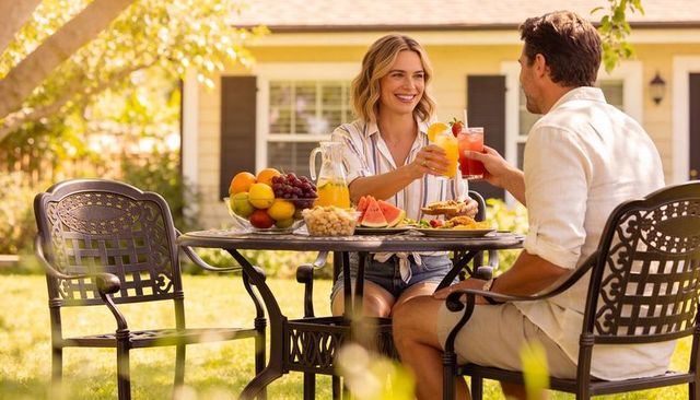 Couple toasting on sunny backyard patio with fresh fruit pitchers and casual summer brunch