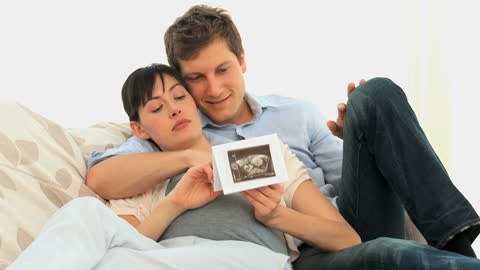 Expectant Couple Viewing Baby Ultrasound on Couch