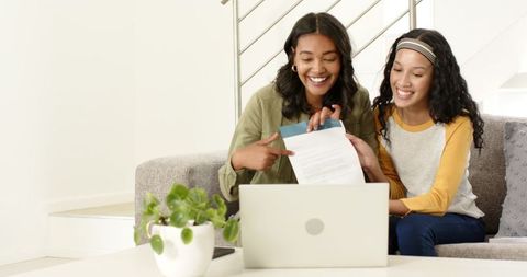 Two Women Smiling While Video Chatting on Laptop in Comfortable Home
