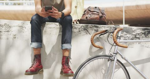 Urban hipster using smartphone with bicycle nearby