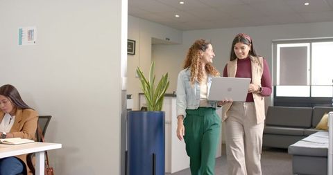 Diverse coworkers collaborating with laptop in modern office lounge