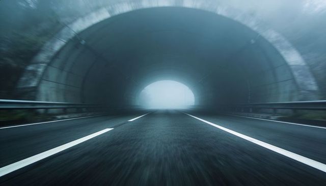 Foggy tunnel highway at dawn low-angle wet asphalt leading lines dramatic perspective