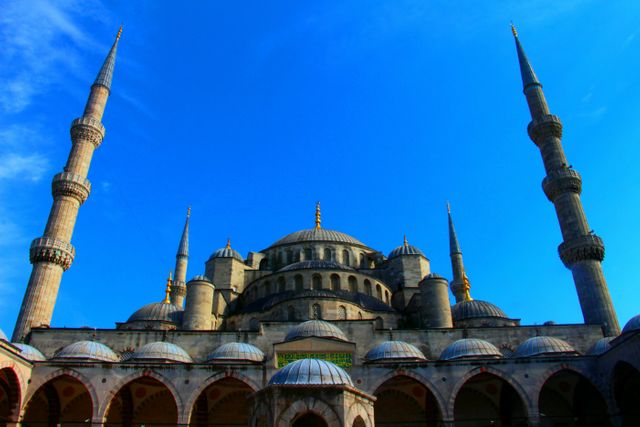 Blue Mosque in Istanbul on clear day with sky, showcasing majestic domes and minarets. Useful for tourism blogs, travel guides, cultural heritage articles, and educational materials focusing on historical sites, architecture, and Islamic culture.
